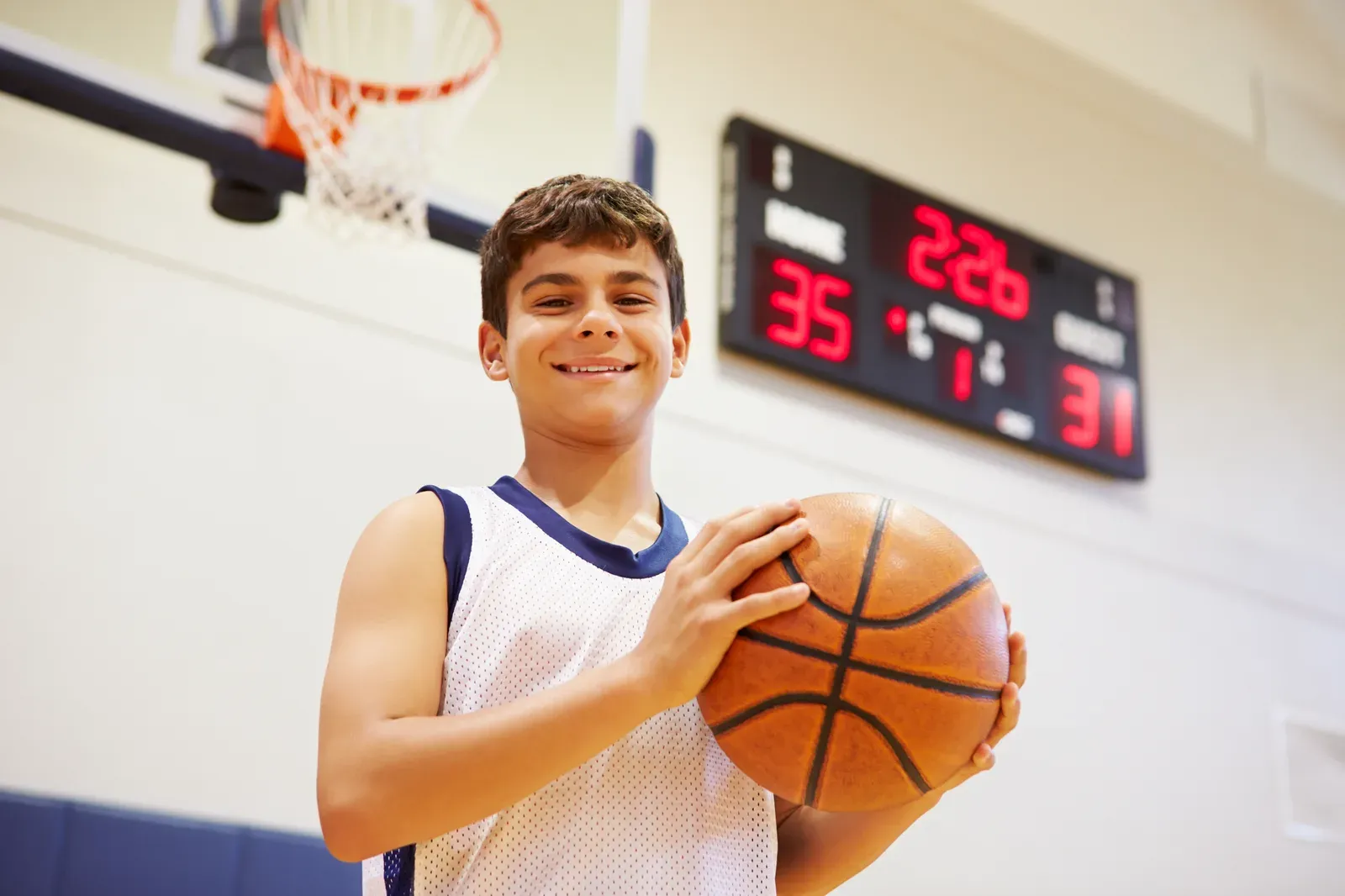 A basketball player jumping to grab a rebound during indoor practice