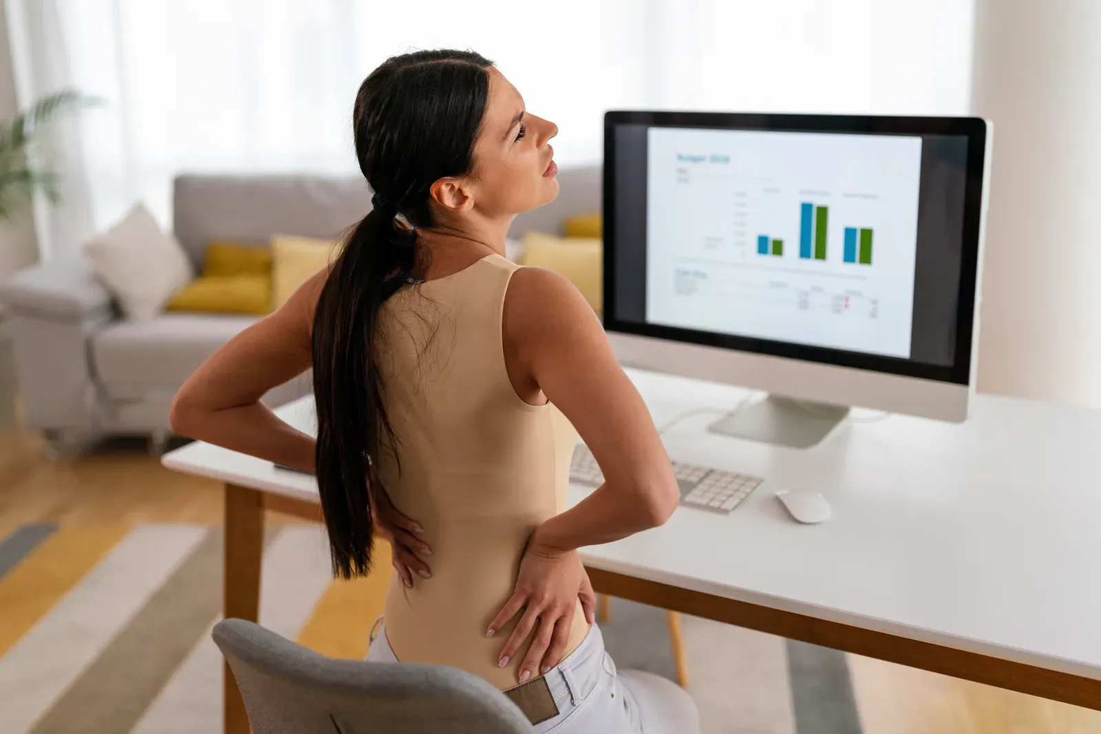 Office worker leaning toward a laptop with the head drifting forward over the desk