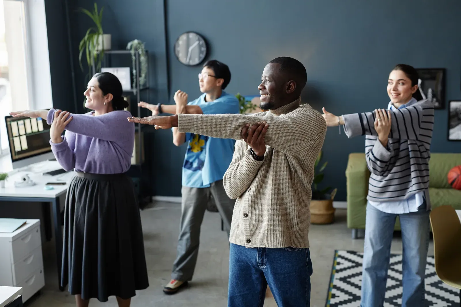 Office professionals stretching their arms during a workday movement break
