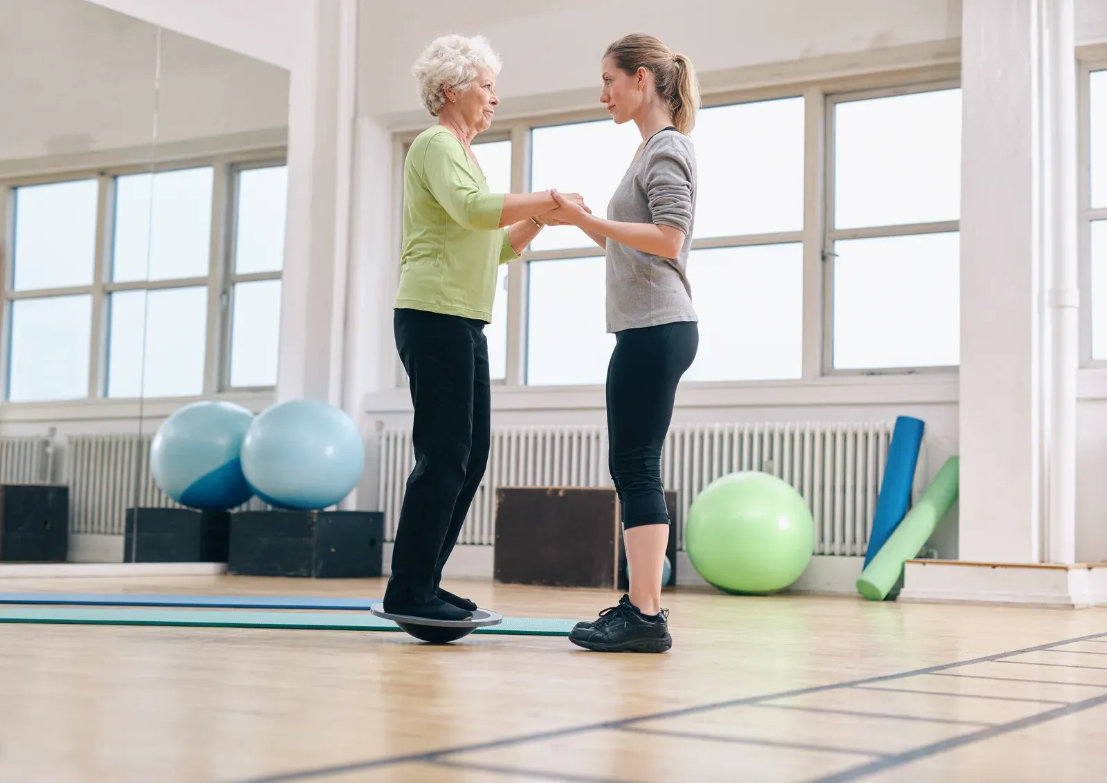 Coach steadying an older adult as she practices a supported step-up
