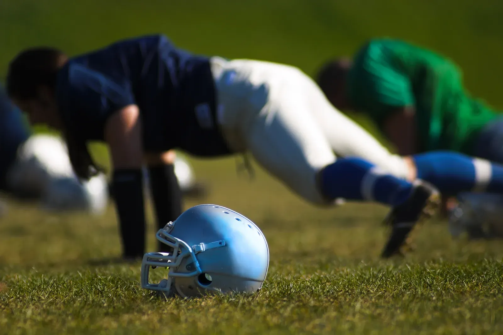 Football athlete driving a weighted sled during an evening field workout