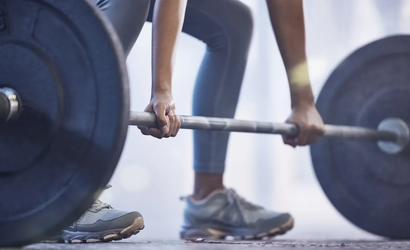 A woman's hands gripping a barbell partway through a strength workout