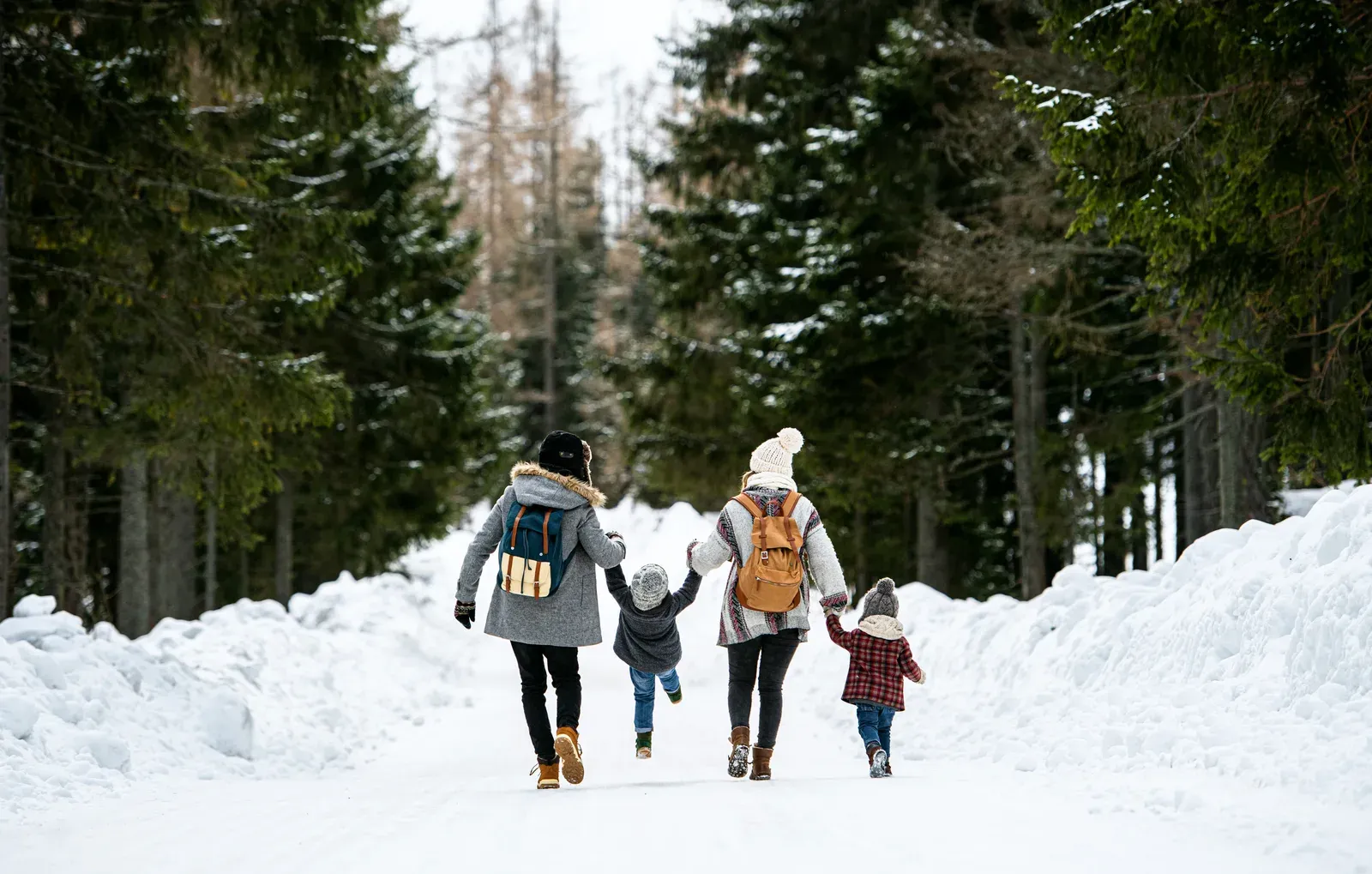 A family with two young children walking together through fresh snow
