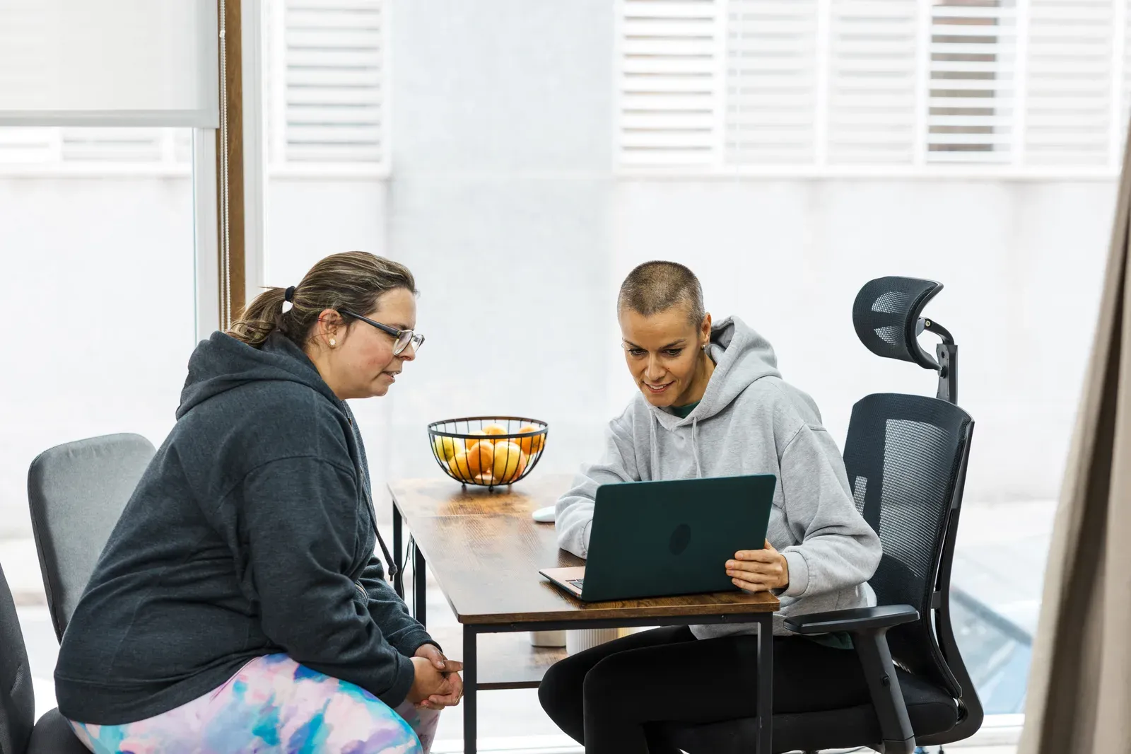 Personal trainer walking a prospective client through a workout plan on a laptop