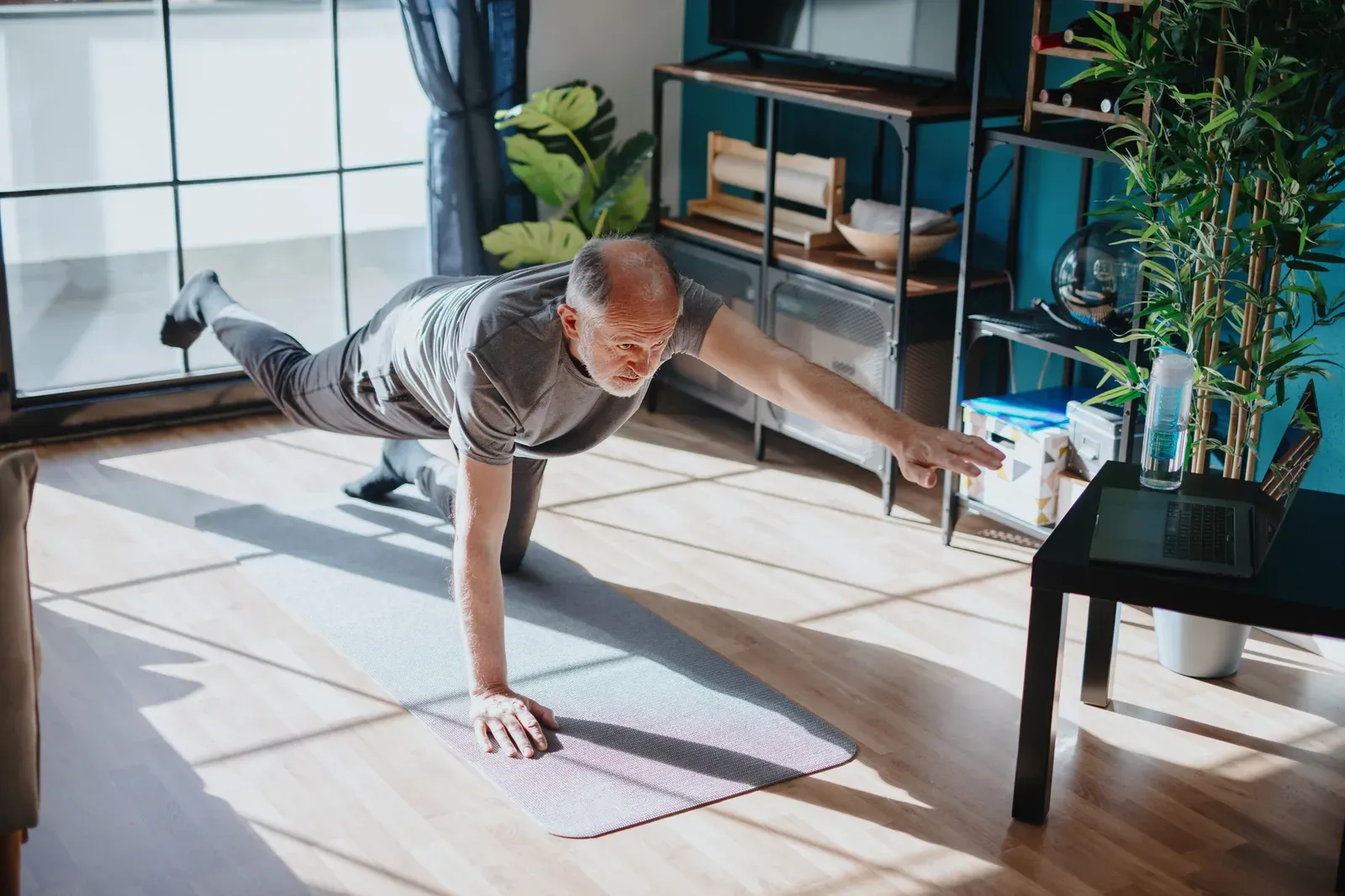 Senior man holding a steady one-leg balance position during a coached session