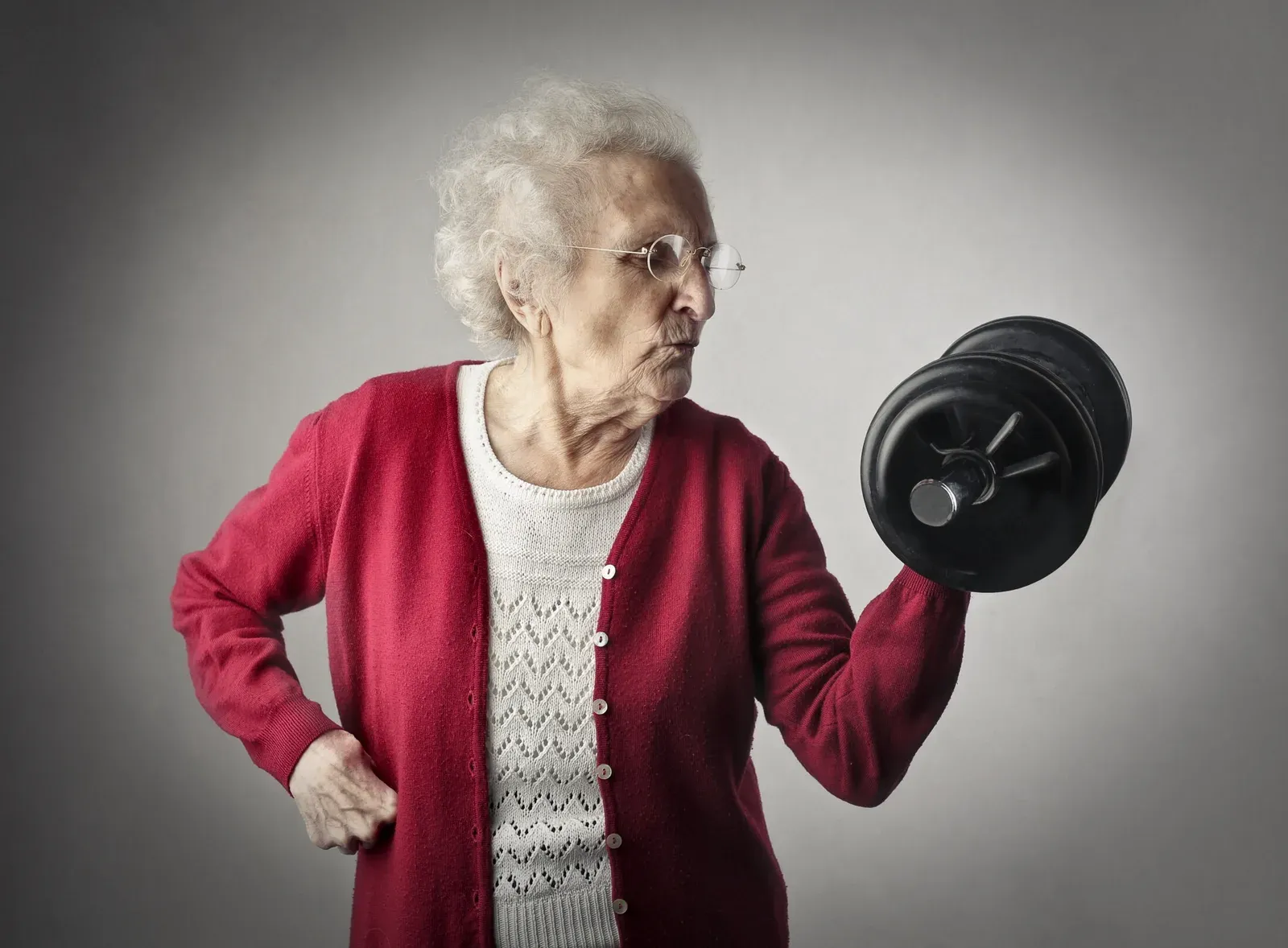 An older woman lifting a pair of light dumbbells