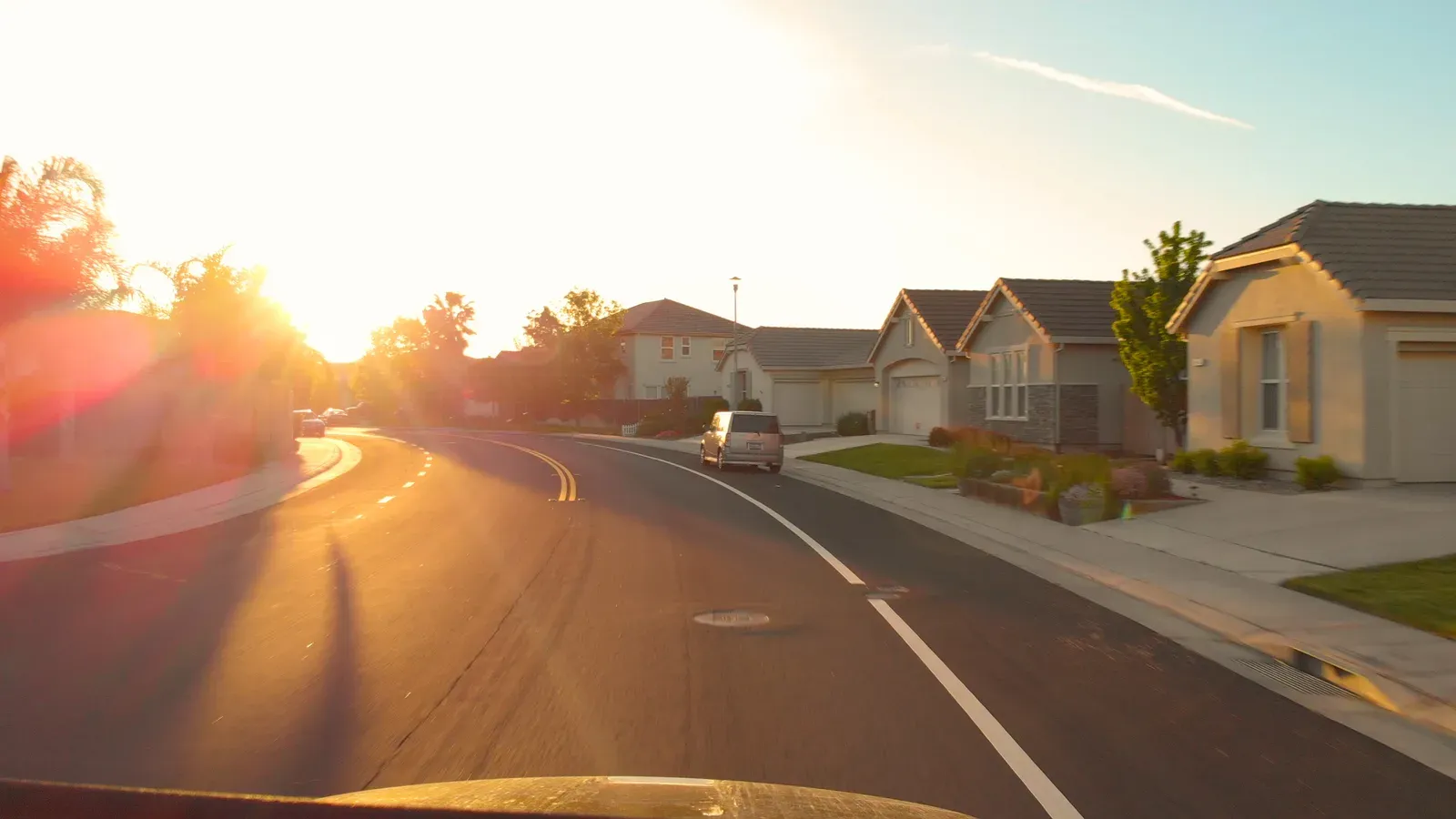 Curving residential street washed in low golden evening light