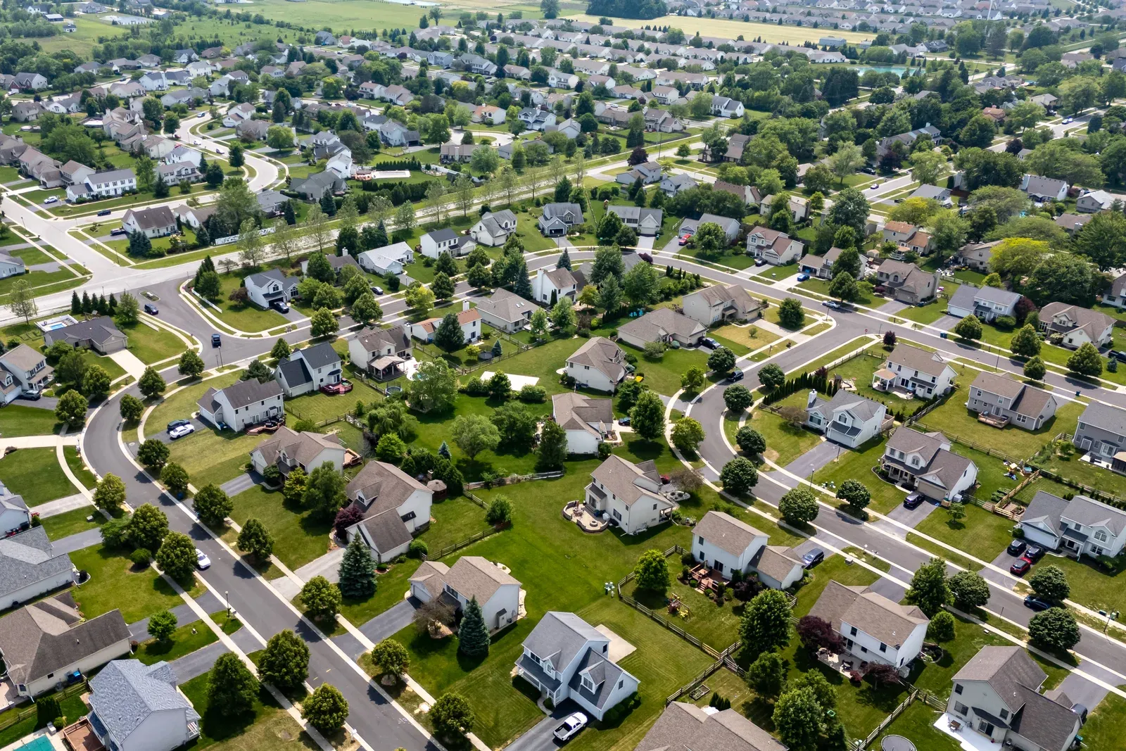 Aerial view of a spreading subdivision with farmland still at its edges