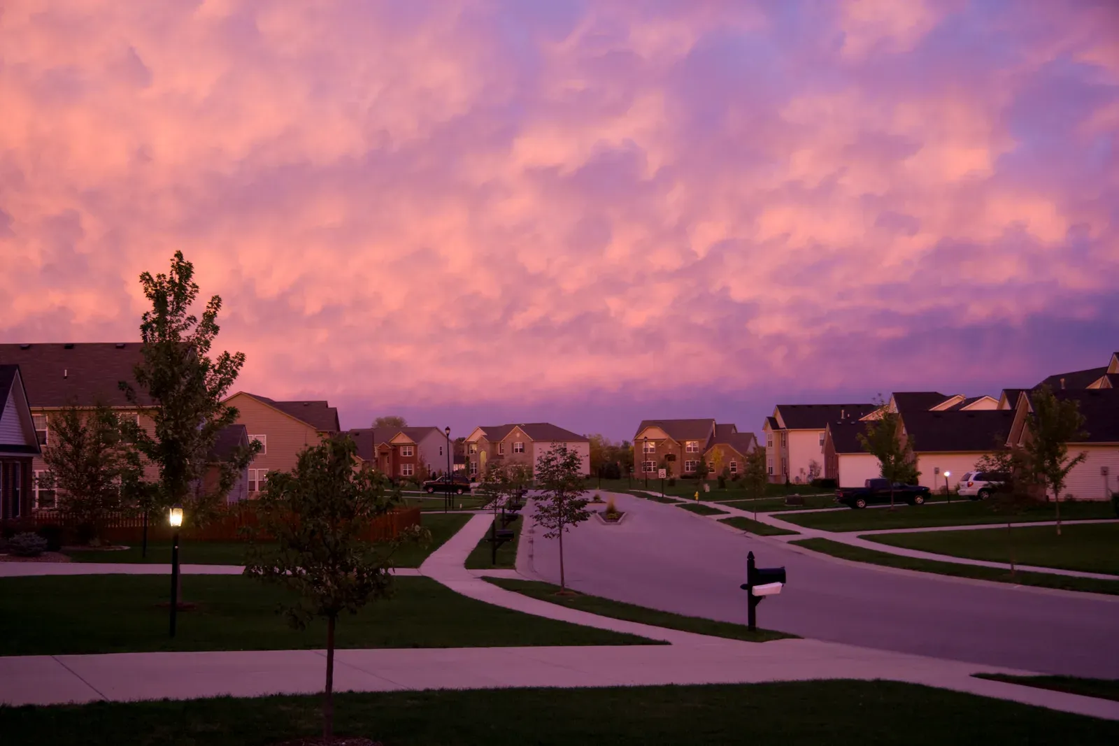 Quiet subdivision street under a pink and purple evening sky