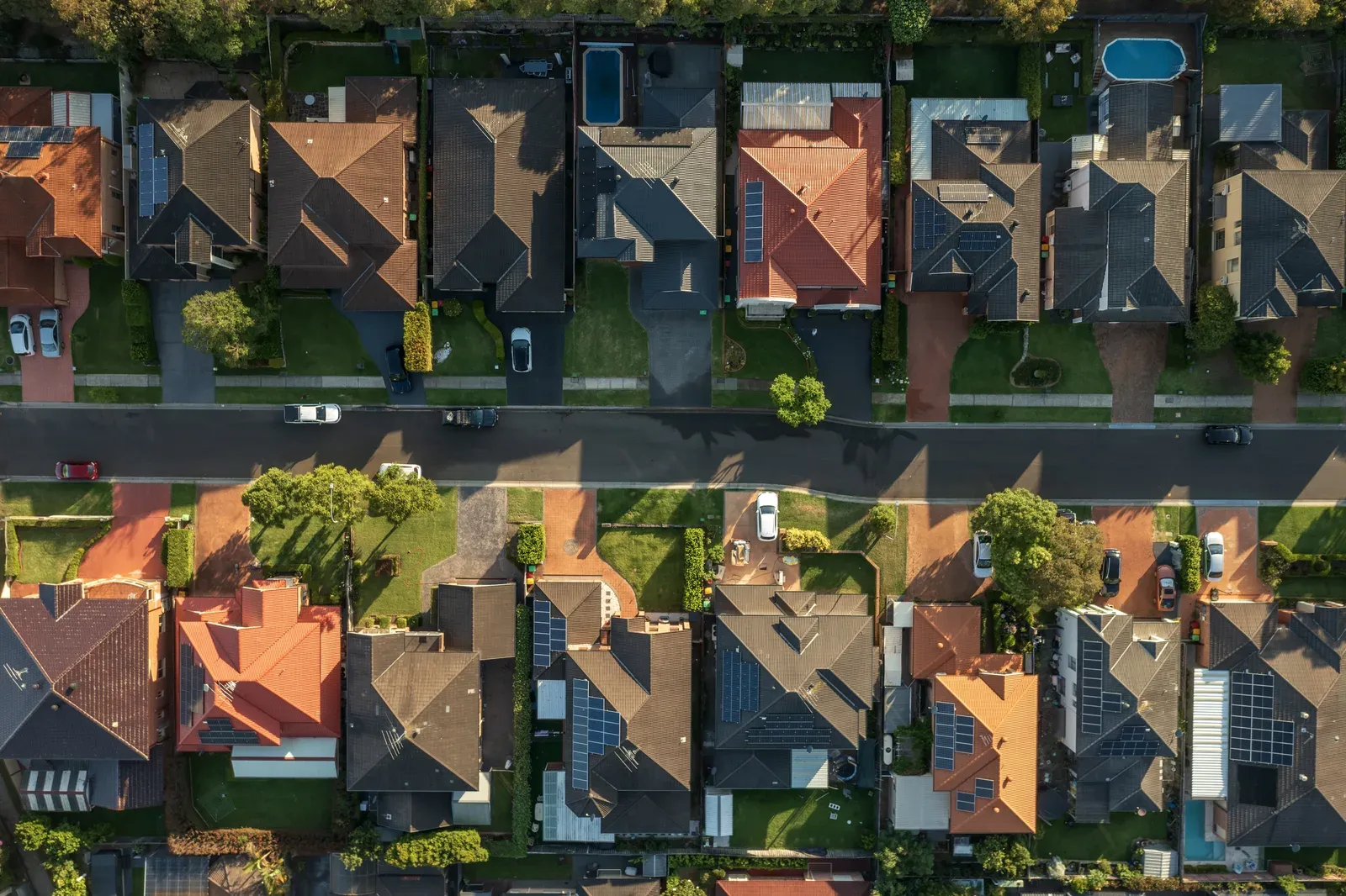 Overhead view of rooftops and tree filled yards along a residential street