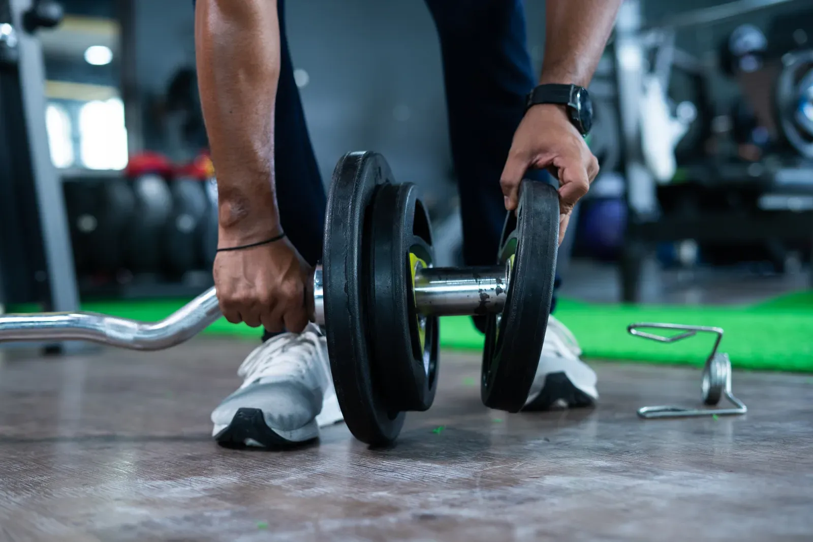 A pair of hands loading a weight plate onto a barbell before the next set