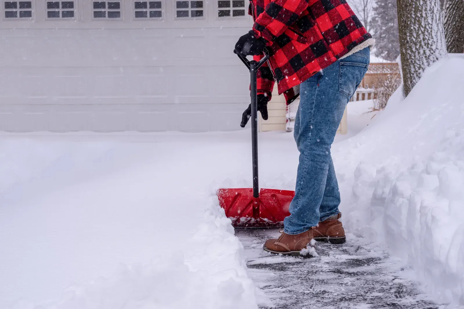 A man shoveling heavy snow off a driveway after a winter storm
