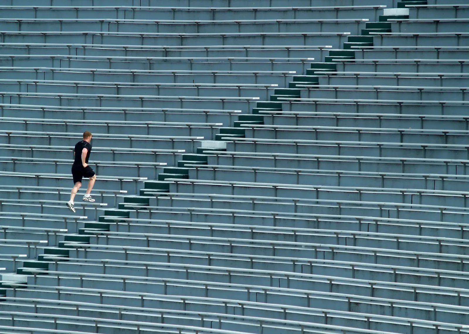 A man running up stadium bleacher steps for a stair workout