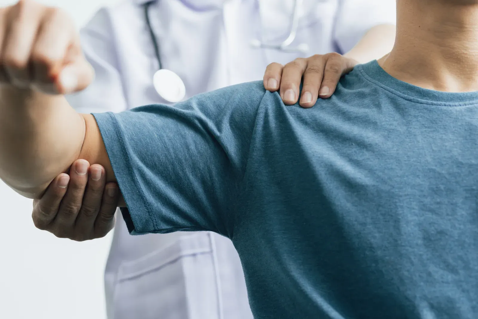 A clinician examining a man's shoulder during a physical therapy visit